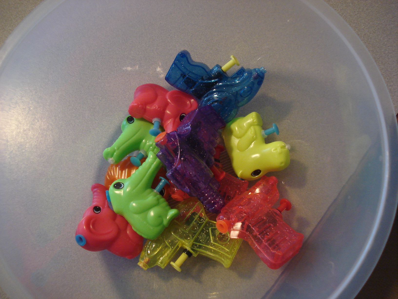 a bowl full of small plastic toys including a bus and a bear