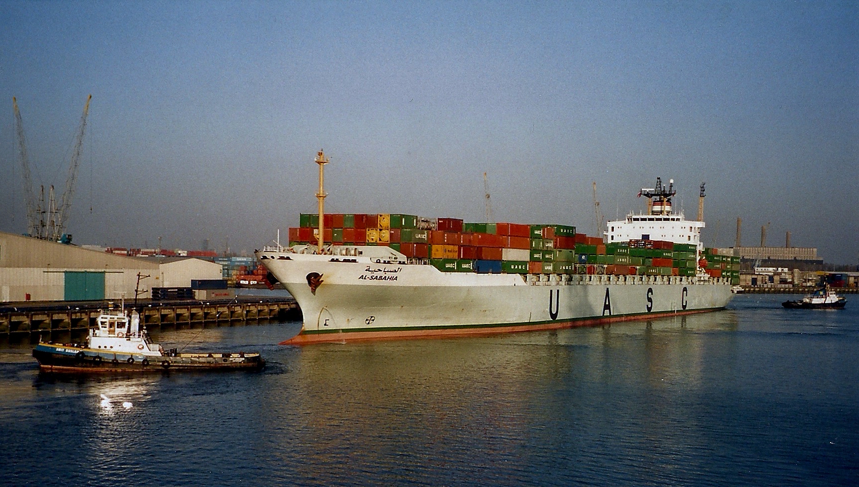 large cargo ship with numerous shipping containers stacked in dock