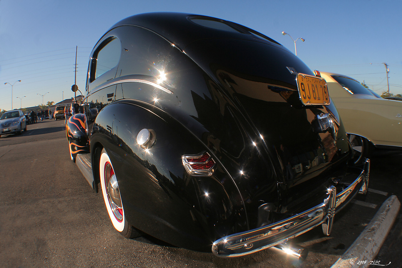 an old fashioned black car parked next to other vehicles