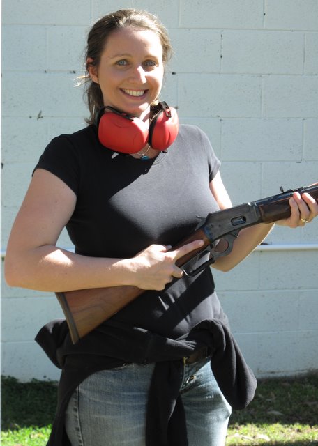 a woman is standing outside holding a gun