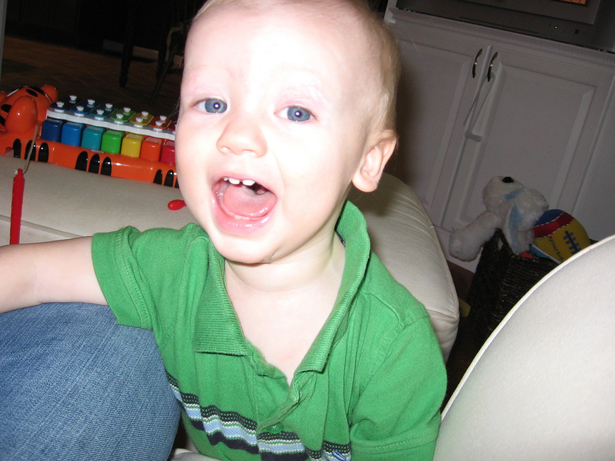 a toddler in green shirt sitting on chair with pens