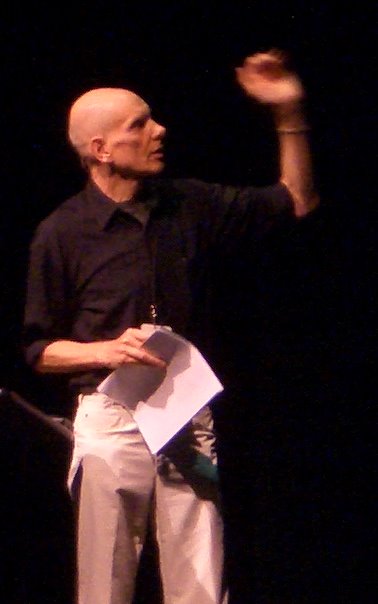 a man holds his hand up as he stands on stage