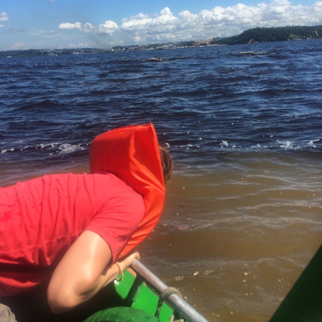 a person with red hood on in a green boat looking down