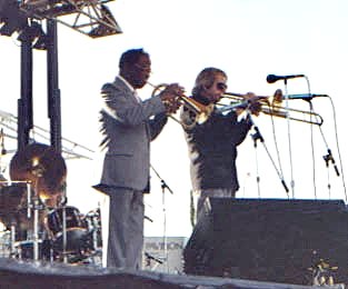 two men playing instruments on stage in front of microphones