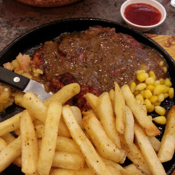 a pan with french fries and meat in it