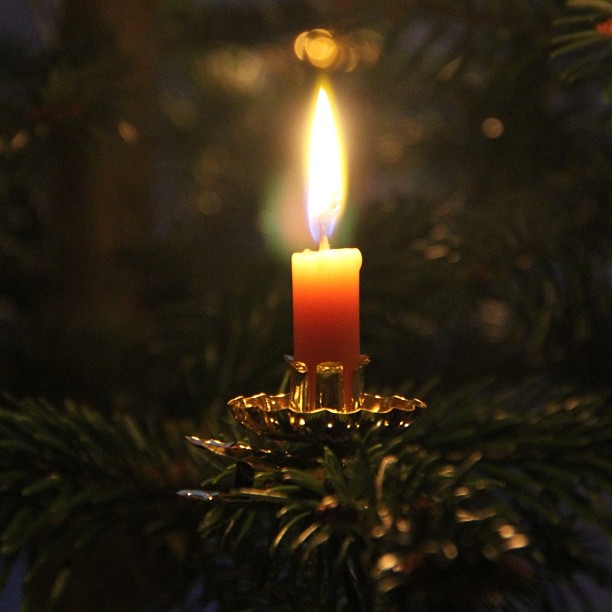 a single candle glowing brightly from a lit christmas ornament