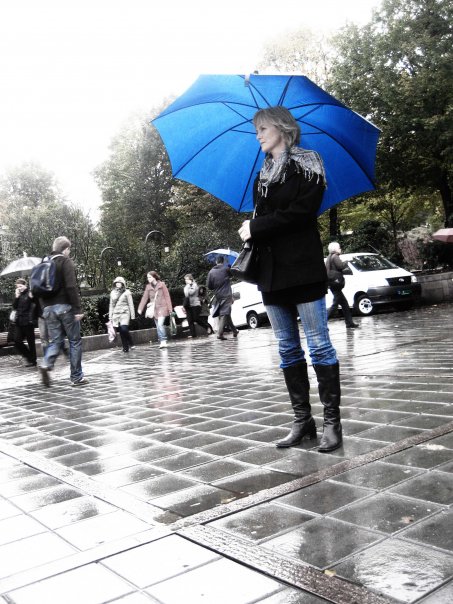 a person in a black coat with a blue umbrella