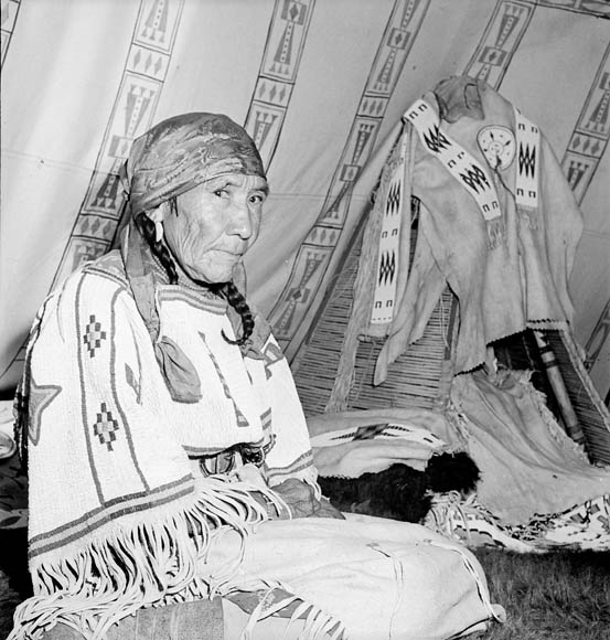 native american woman sitting next to a teepee with an arrow