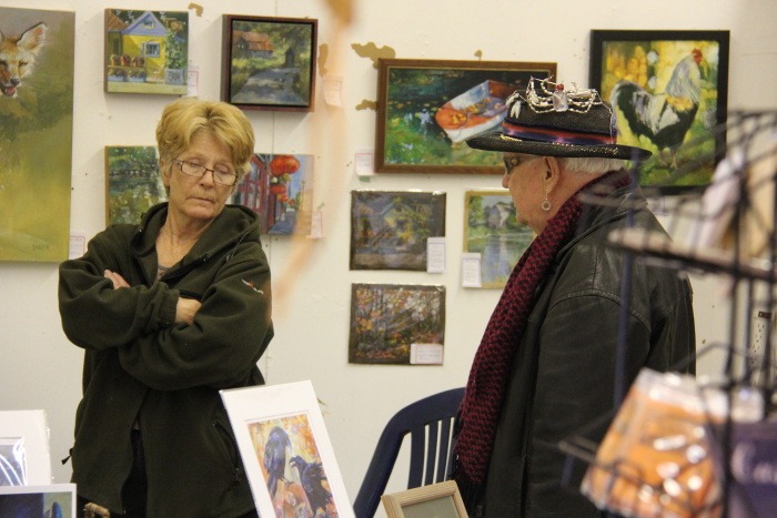 a man and a woman in black jackets looking at paintings