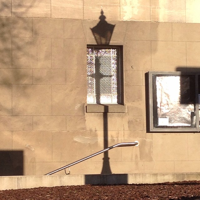 the shadow is cast onto a street light on the side of a building