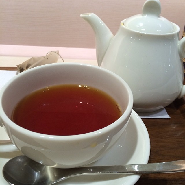 a teapot and saucer on a plate with a cup of tea next to it