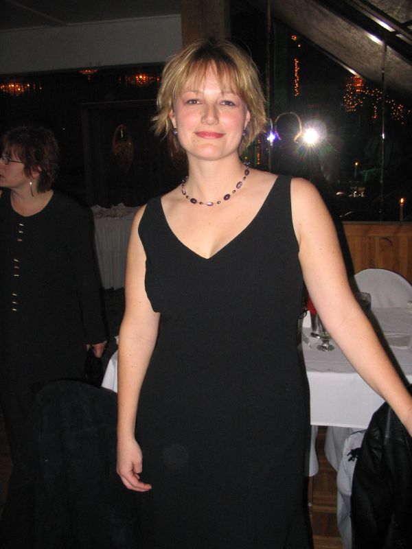 a woman with blond hair wearing a black dress and necklace