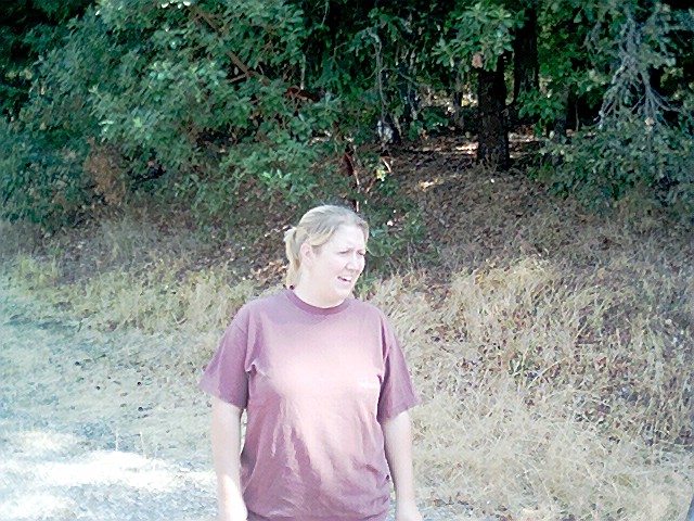 a woman standing in a dirt road smiling