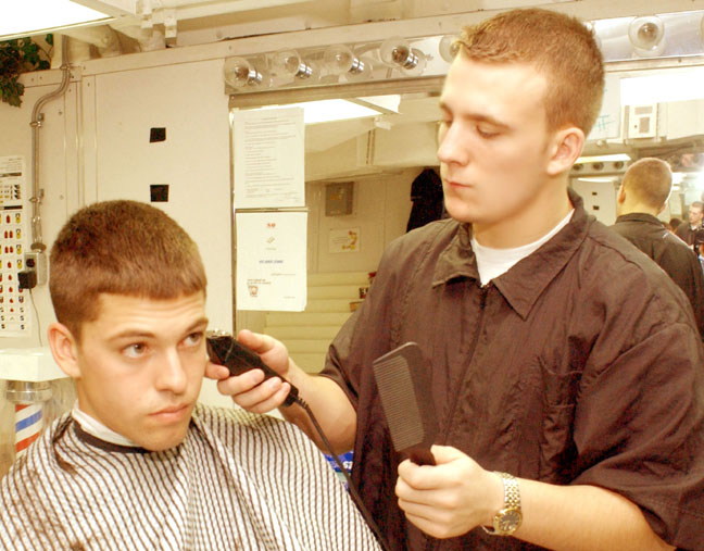 a boy getting his hair cut by a person