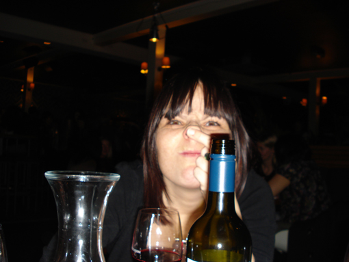 a woman smelling the cork of a bottle of wine