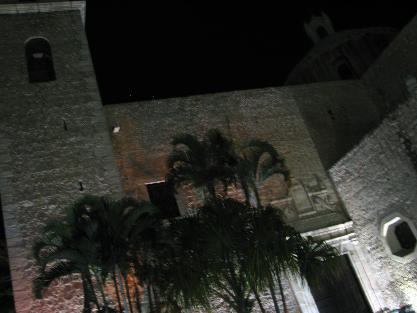 a tall gray building with a clock and palm trees