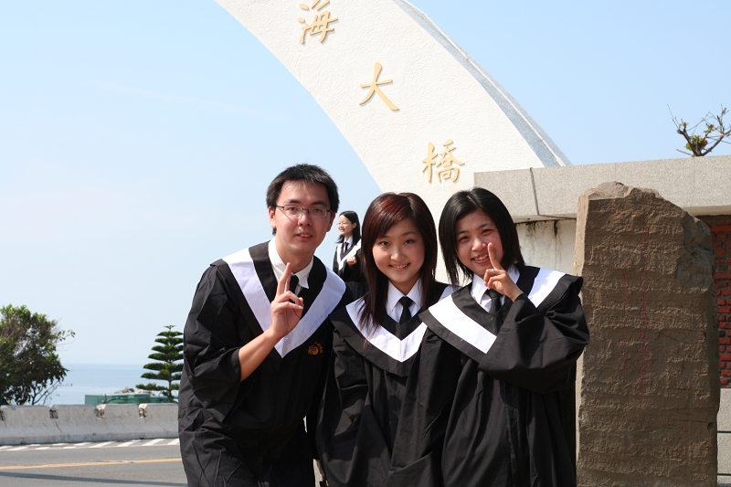 three graduates pose in front of the chinese arch