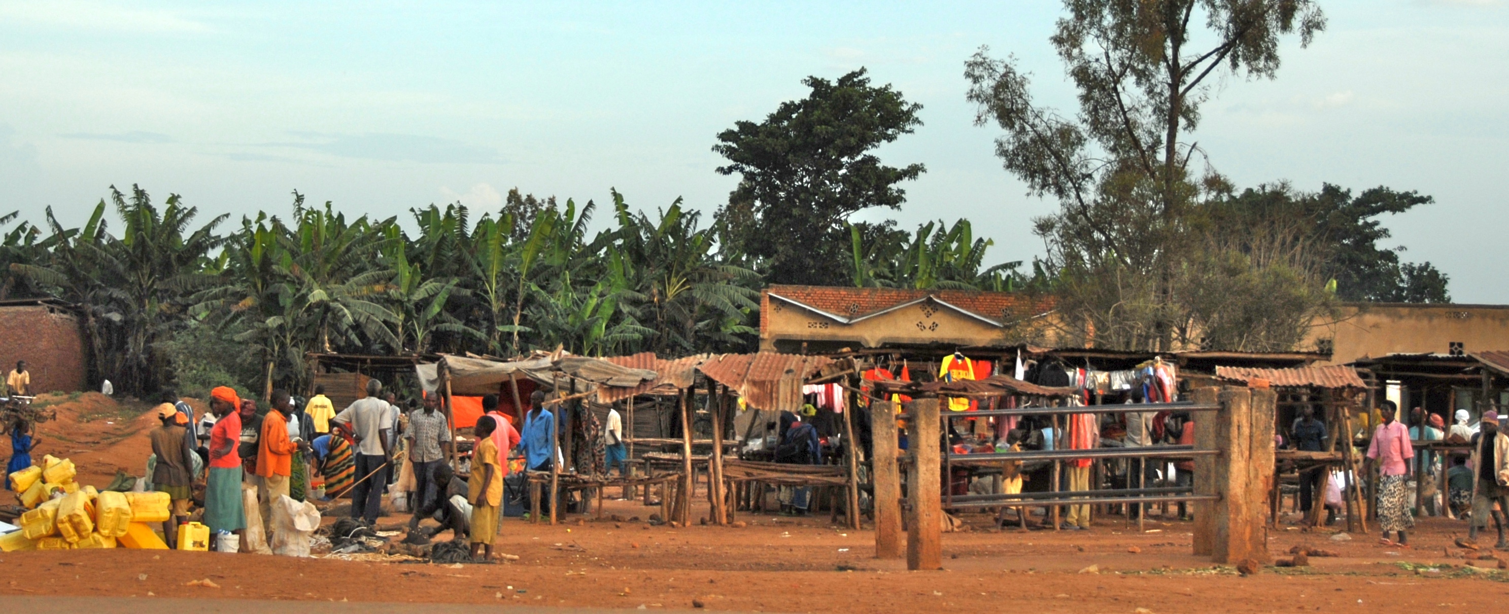 several people outside of their village with some houses and a lot of trees