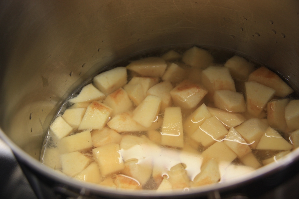 cooked potatoes in a pot with milk being stirred