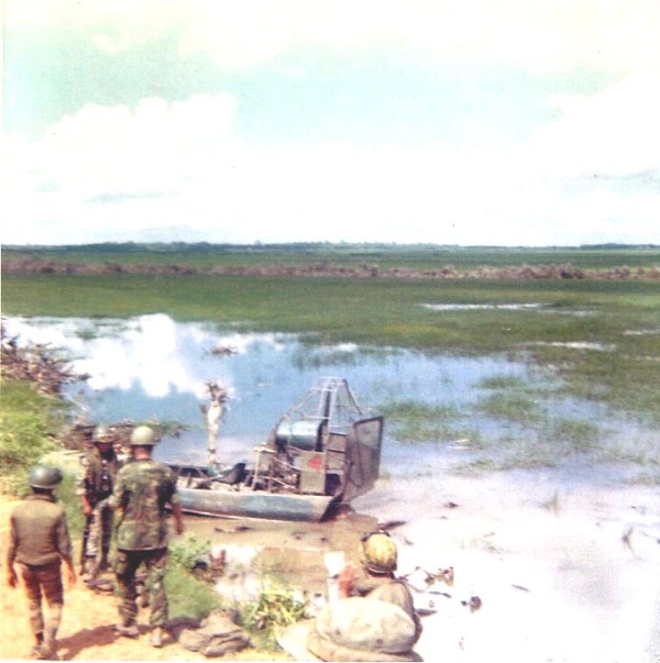 soldiers standing near a boat in the water