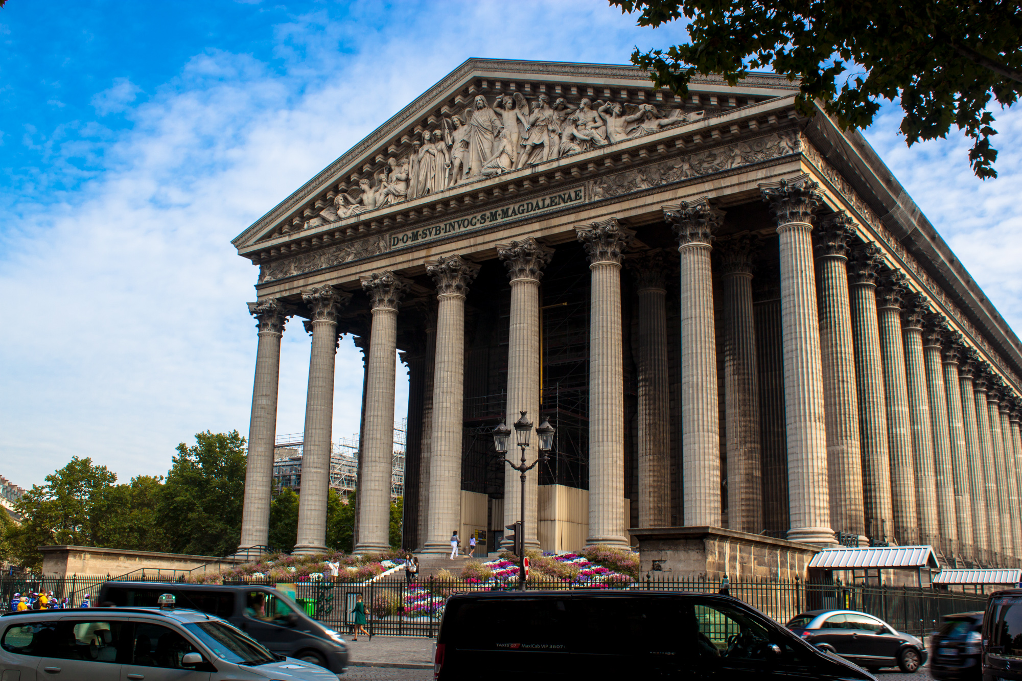 a building with columns and arches over cars in front