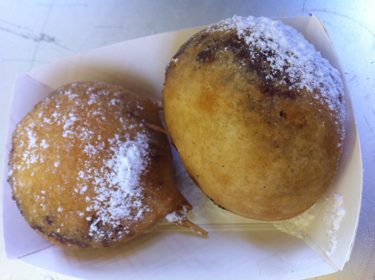 two pastries covered with powdered sugar sit in a box