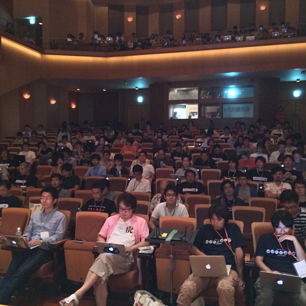 large group of people working on laptops in an auditorium