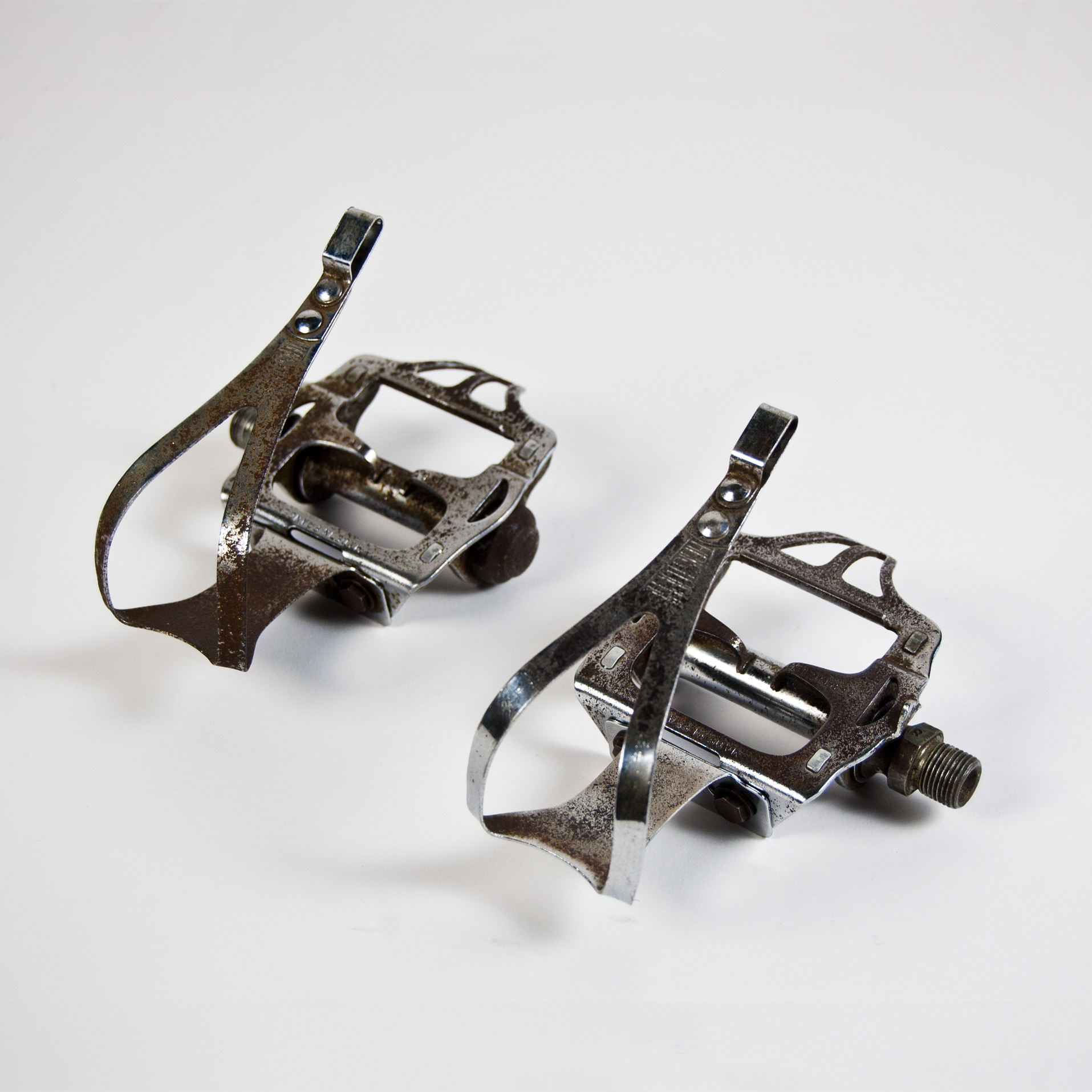 two silver pairs of bicycle pedals against a white backdrop