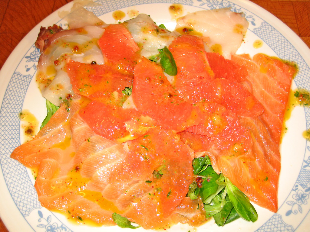 a plate topped with salmon and vegetables next to a container of soup