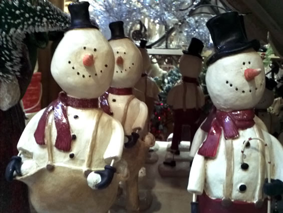 three snowmen stand in the middle of christmas decorations