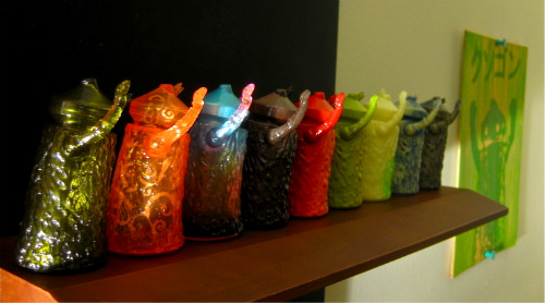 seven multi - colored candy bags sit atop a wooden shelf