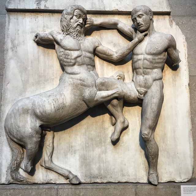 two men wrestling in the middle of a statue