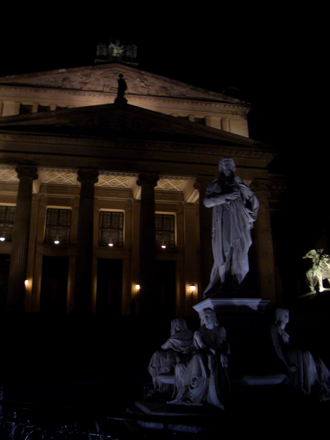 a statue stands outside a building in the dark