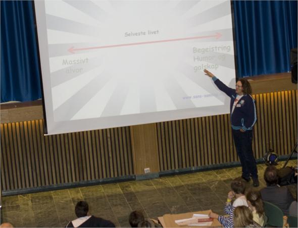 woman standing on stage giving a presentation to students
