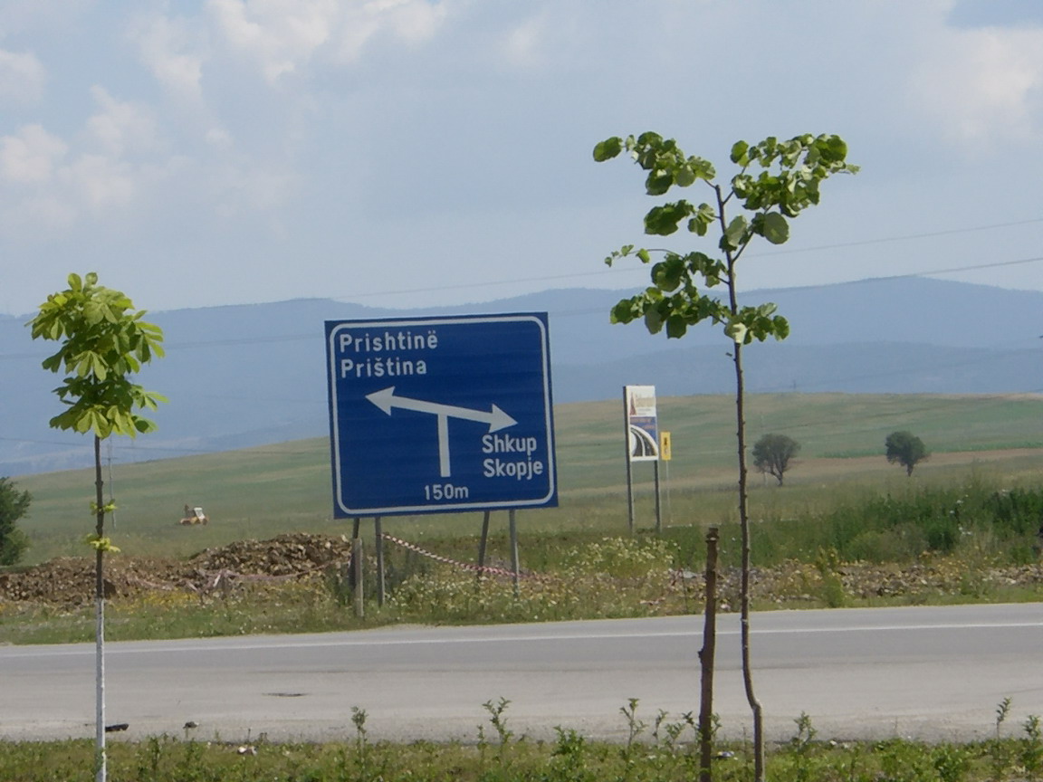 a blue and white sign sitting on the side of a road