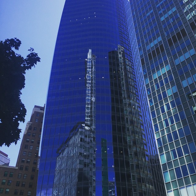the skyscrs in the city are reflected off the glass windows