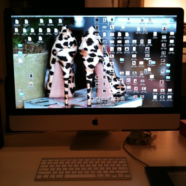 a computer monitor with a pair of high heels on it
