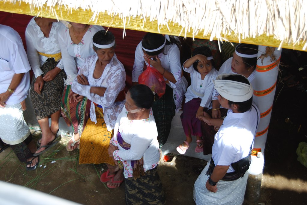 people dressed in white standing next to a small structure