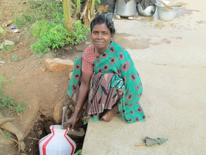a woman kneeling down by a well for water
