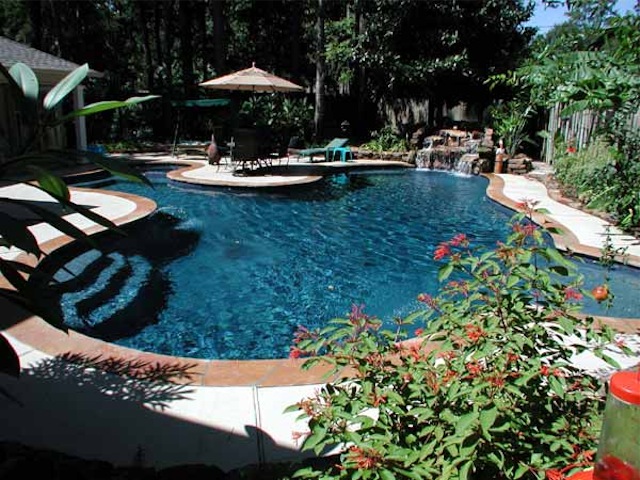 a pool with a garden, umbrellas and other items next to it