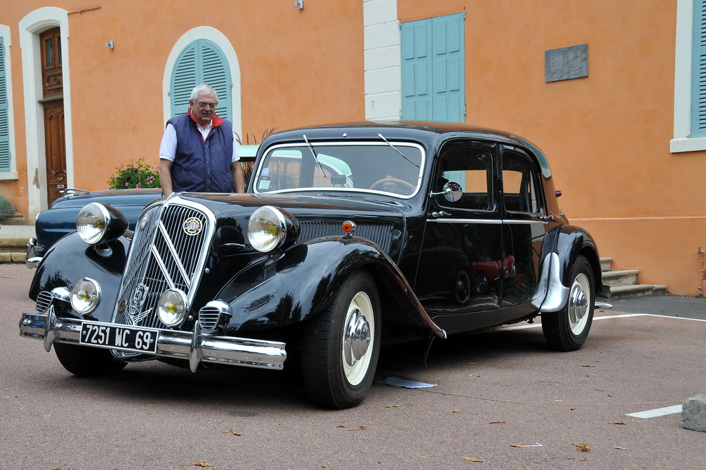 a vintage black car parked in front of an orange building