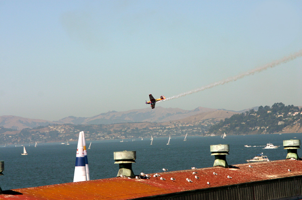 a small plane flying low to the ground in front of a body of water