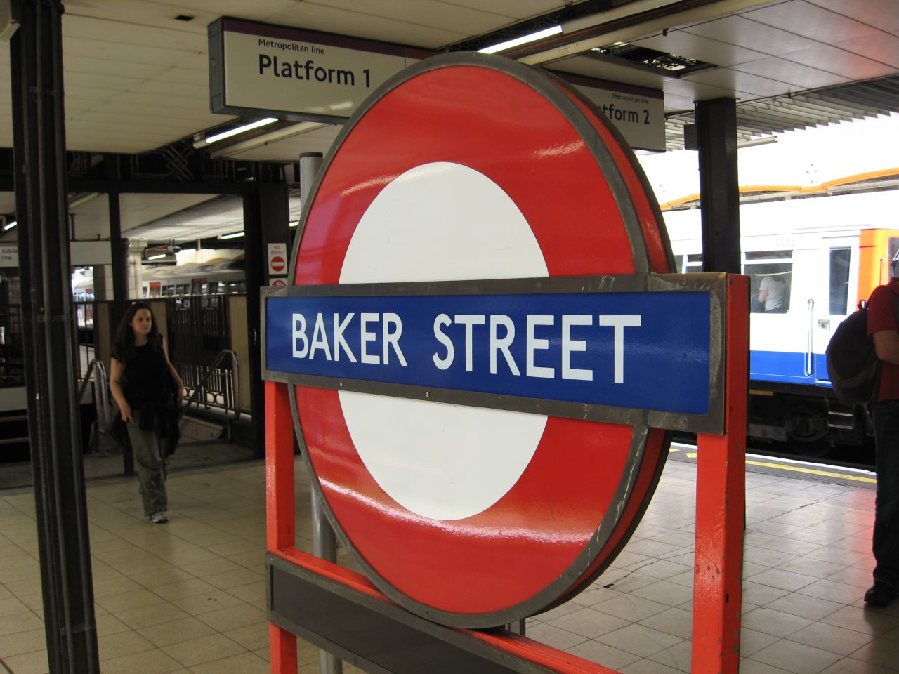 a red and white sign sitting on top of a train station platform