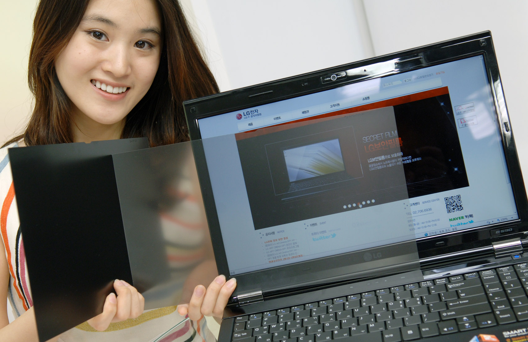 girl in striped shirt holding up a book and a laptop