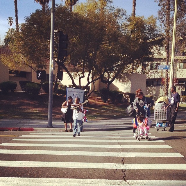 a group of people crossing the street near some trees