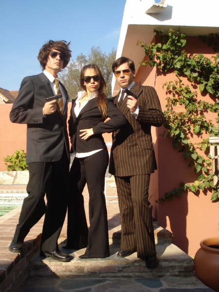 three people in suits and sunglasses stand together