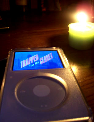 an ipod with a lit candle in the background