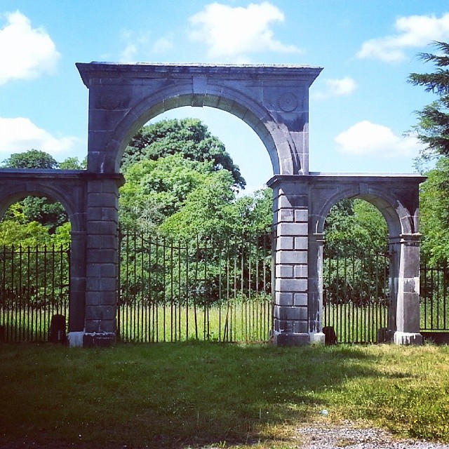 a fence with two archways is in front of a grassy area