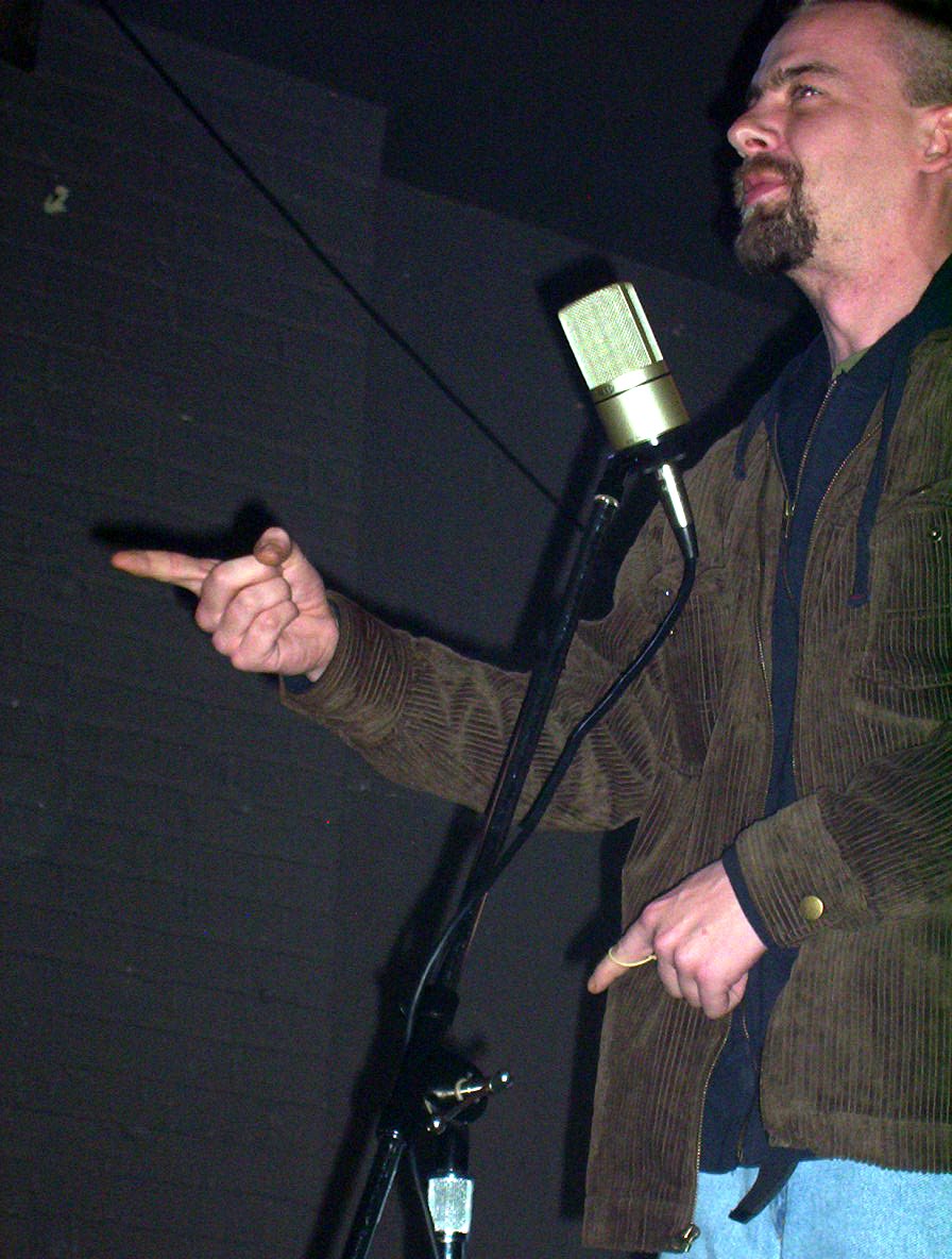 a man with a microphone and pointing to soing