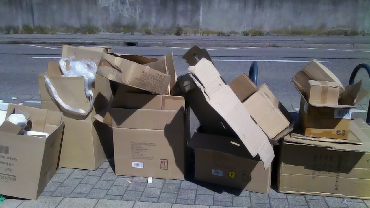 a pile of cardboard boxes sitting next to a sidewalk